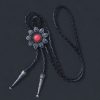 Vintage silver bolo tie with a floral design, featuring a turquoise or red stone centerpiece and a braided leather cord.