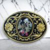 Western belt buckle with resin-protected raw gemstone featuring a gold and black enamel floral design, crafted from durable metal alloy for a stylish look.