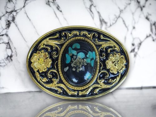 Western belt buckle with resin-protected uncut turquoise gemstone featuring a gold and black enamel floral design, crafted from durable metal alloy for a stylish look.