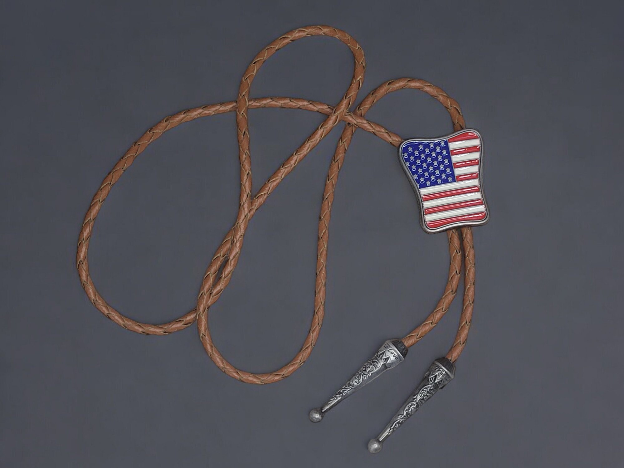 Western Wear Patirotic American Flag Bolo Tie With Genuine Cowhide Leather Cord (7) Western-style bolo tie with American flag design, braided leather cord, and metal tips.