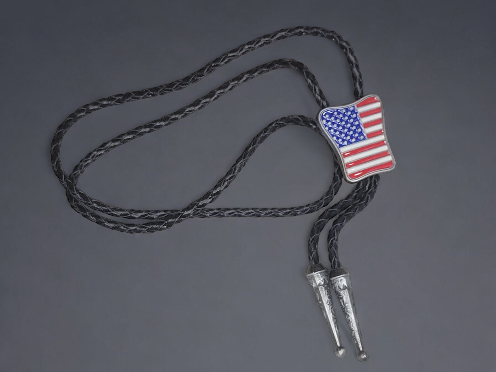 Western Wear Patirotic American Flag Bolo Tie With Genuine Cowhide Leather Cord (8) Guitar-shaped bolo tie with braided cowhide leather cord, metal tips, and adjustable slider clasp.